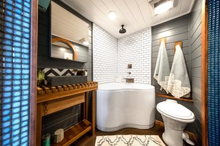 On the opposite end of the dining area is a spa-like bathroom with sliding arched doors, Moroccan tile trimming, a walk-in closet, toilet, rain shower, and a corner bathtub.