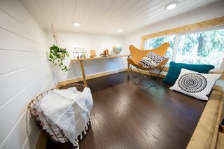 Above the dining area is a lofted lounge and office space with a small desk, chair, and cushions.