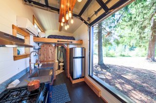 Thanks to the large window on one side that frames the natural scenery outdoors, the house feels much larger than its actual size.