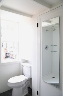 The bathroom fits a shower, vanity with roll out drawers, porcelain toilet, and hookups for a washer/dryer combination unit, as well as storage.
