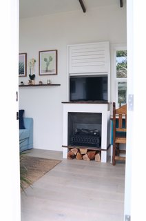Built into the wall near the sofa bed is an electric fireplace with a smart television above it.