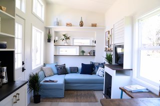To one side of the entrance door is a large, light blue, lounge-style sofa bed.