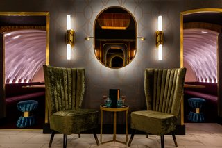 The intimate, den-like space has vaulted ceilings, wood-paneled walls, and chairs and stools upholstered in olive, coral pink, and turquoise velour.