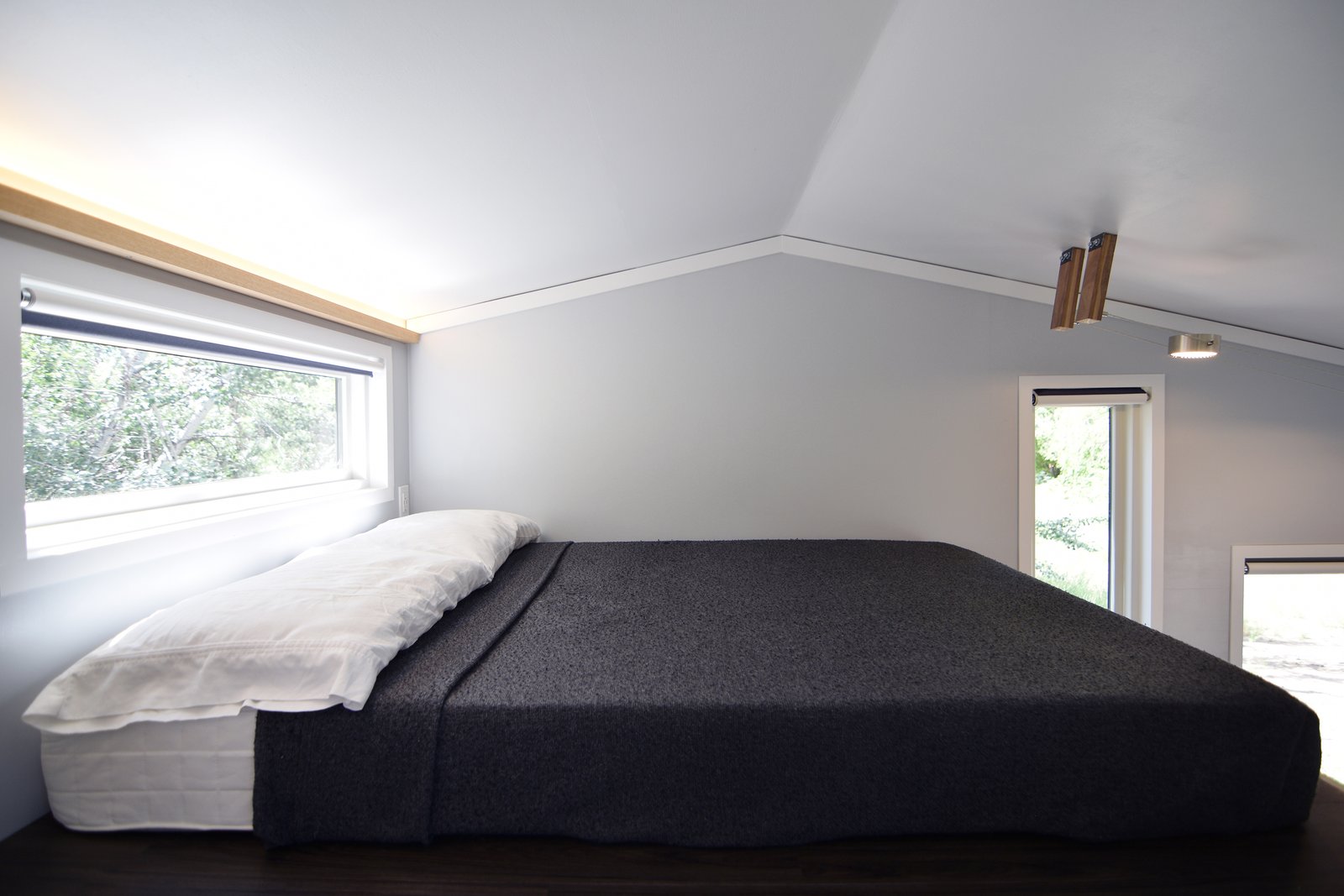 Up in the loft, a full size mattress is set parallel to the length of the house, with a strip of window gently illuminating this rest area.
