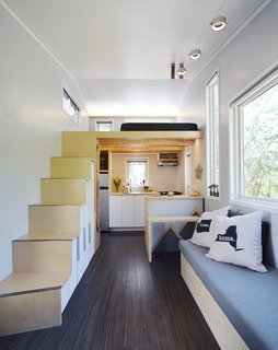 The kitchen is fitted with a compact propane stove top and oven, as well as a refrigerator, sink, and a pantry behind the stairs.