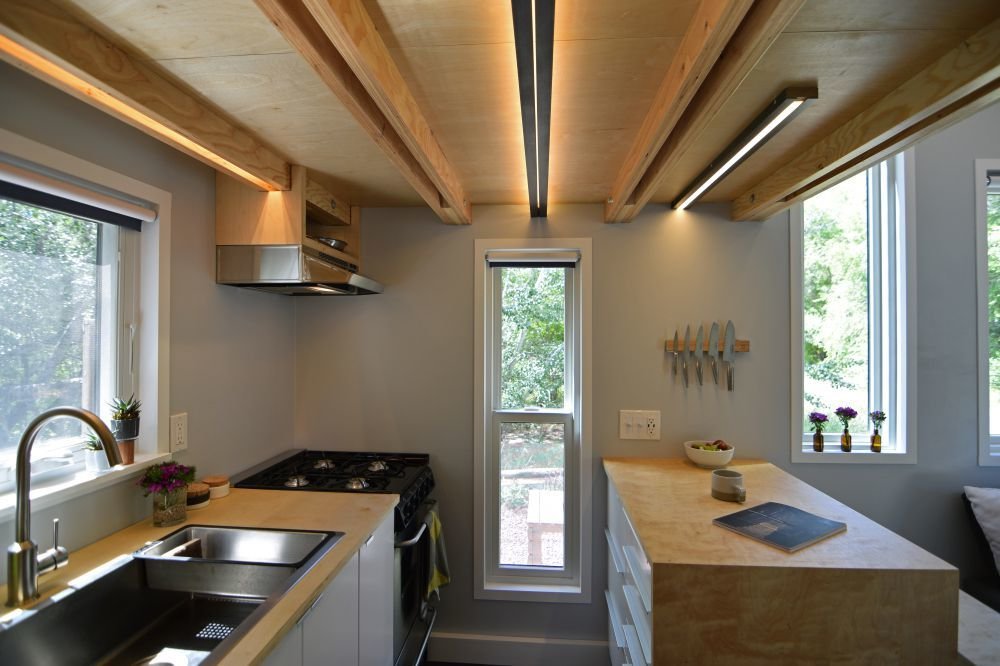 The galley-style kitchen is located below the sleeping loft, and has identical operable windows on each side to bring in an abundance of light and cross breezes, while opening up the interiors to views in both directions.