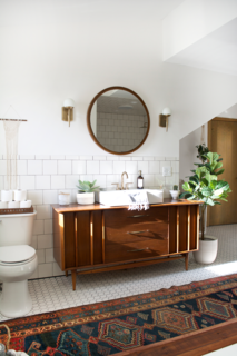  She has always adored mixing old and new furniture, so she knew she wanted to find a vintage dresser to serve as the vanity. "It took some time, but I eventually found the dresser at a local antique store that was the perfect size," she explains. Once she found it, she had a vessel sink and a Delta faucet in champagne bronze incorporated. Another one of Bertolini's favorite vintage pieces is the rug from Swoon Rugs. 