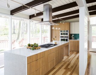 The team chose two-tone Eclipse Cabinets with Thermally Fused Laminate (TFL) doors in Arizona Cypress and White Zebrine, a colorful backsplash from Fireclay Tile in a picket shape and Bora-Bora color, a Kohler Vault sink, and a Hansgrohe faucet. 