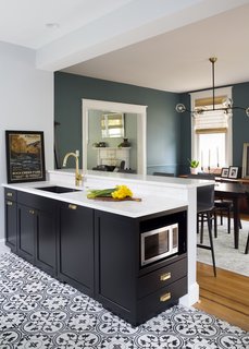 The microwave was discreetly located at the end of the new peninsula. The new layout allowed for the feature wall to highlight the 36-inch, pro-style range with highlighted tile niche storage. 