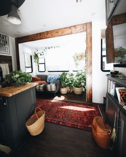 The original trailer had beige walls, wood-veneer cabinets, carpet, vinyl-tile flooring, and gray plaster counters. The couple thought the shades of brown and veiled tones made the space seem dark, so they infused as much bright and light-colored accents as possible. They painted all the walls white and chose a dark matte gray for the cabinets, which complement the black appliances, window edges, and light switches.
