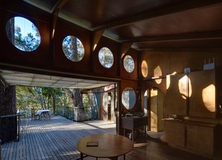Located within the open area are a laundry and storage area, and a toilet with portholes that present views of the bush cliffs above. 