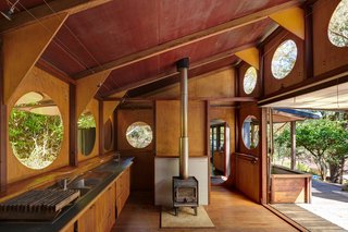 The work areas of the kitchen consist of a three-burner cooktop—which sits on a custom-designed trolley—and floating cabinets that incorporate sinks, an underbench oven, and plenty of storage. 