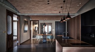 Within the open-plan living, dining, and kitchen space, KC Studip created a second ceiling in the form of three brick arcs that extend from one girder to the next, with each gentle arc rising over one of the functional zones. 