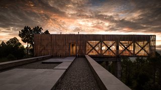 The impactful dining room is surrounded by glass on three sides and clad in bamboo sticks that reduce the visual impact of the steel structure.