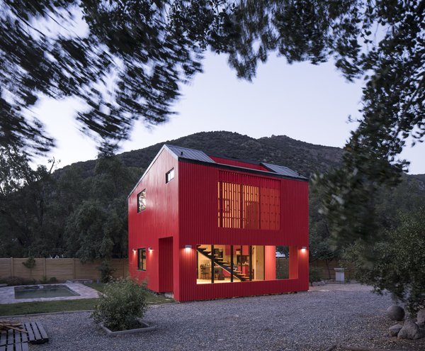 The distance between homes in the area allowed architect Felipe Assadi to make a grand gesture by painting the two-level house bright red to complement the intense green of the surrounding trees, and to "activate the relationship between the landscape and the project through contrast."