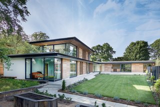  An entrance hall, gallery, and double-height staircase connect the two wings, which frame views of the serene garden. 