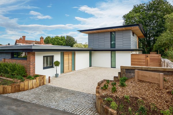 The simple building materials —brick, timber, off-white render, glass, and zinc— and the elevation of the house take its cue from Manor Court.