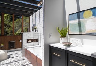 The toilet is hidden behind a tiled wall-partition at the foot of the tub.