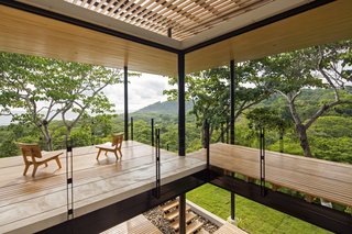 The front of the house is composed of expansive, open terraces that look toward the boundary between the ocean and the jungle.