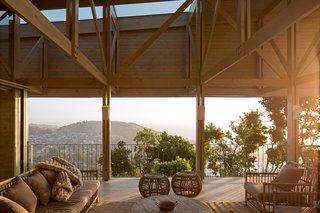 Built with thick stone walls that create two horizontal planes in between the forest, the house has a roof made of glass and steel.