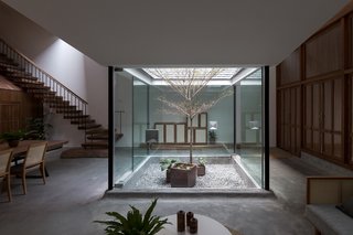 Passing through a patio and entranceway, one enters an open-plan living and dining area with ceilings that dip towards the four glass walls of the small interior garden.