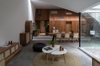 At the back of the living area is a volume shaped like a wooden house, which contains the kitchen, storage space, and a bedroom. 
