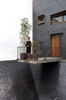 A facade of slate stone and warm wood gives the house a rustic, Southeast Asian character, while high, arched ceilings, and clean lines open up the interior spaces.