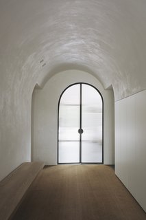 A curved corridor with lowered ceilings serve as the threshold between the home's two wings. 