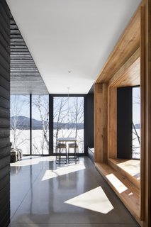 The open-plan living area on the ground floor of the new building is fitted with large windows that frame tranquil views of the lake. 