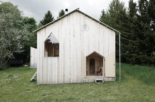 A large pitched-top door, and a small pitched-top window are cut out from each of the four sides of the chalet’s exterior walls.