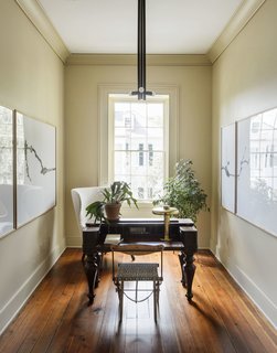 An antique desk, a Lawson Fenning Highland Wingback Chair, a Jim Bindman table lamp, a Workstead Lodge pendant, and art by Brandon Hinman can be found in the office.
