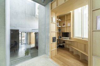 The living/dining room features large expanses of glass walls. These spaces either look out to the green outdoor areas or into the interior voids.