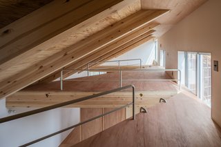 The loft-like spaces tucked high above the ceiling serve as sleeping or storage areas, and are accessible via metal ladders.