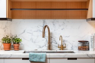 The kitchen features a Calacatta honed marble counter and backsplash, as well as an island with a black granite countertop.