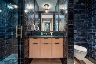 This bright bedroom has a monochromatic bathroom with a spacious walk-in shower that is covered in sleek subway tiles. 