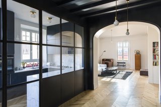 With dark blue walls and ceilings, the chromatic dining area is a striking contrast to the light-colored living area, which has pale chestnut flooring on French-inspired white walls. 