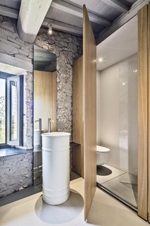 While using the washbasin, the owner can enjoy outdoor views. "The 'rarefacted' wooden wall generates a light visual relationship between bedroom and bathroom spaces," says Cisi.