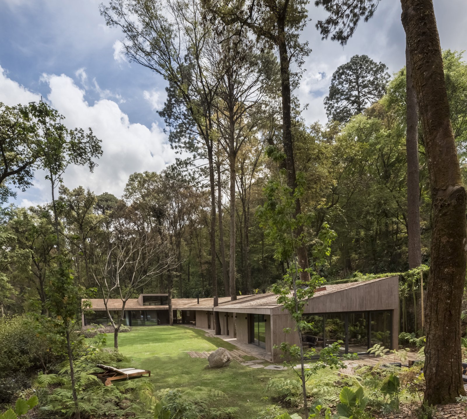 The L-shaped layout embraces a patch of a private garden where the owners can lounge in the sunshine, picnic on the property, and take in views of the nearby lake.