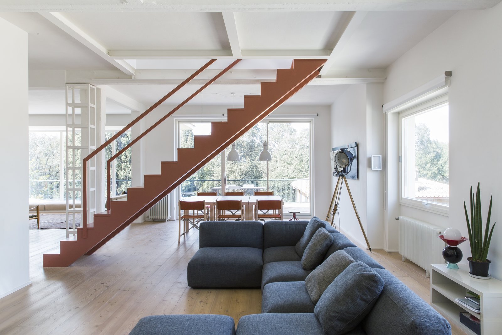 A pink, sculptural staircase appears to float in the middle of the common area, demarcating the boundary between the living and dining areas, and connecting the two levels.