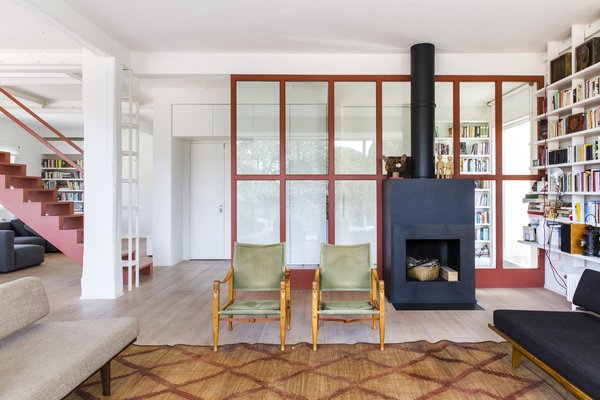 With fresh white walls, larch parquet flooring, and a sleek black fireplace, the apartment now radiates an open, airy environment. A beautiful pink staircase appears to float in the middle of the common area, demarcating the boundary between the living and dining spaces.