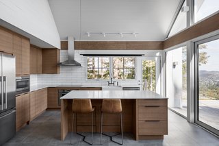 "The family are very close-knit with a lot of nostalgia for a cottage that their grandparents once owned. Things like cedar shakes, painted pine paneling, handmade bed quilts, and ceramic tiles reminiscent of quilt patterns bring those memories back. The clients' children are now young parents with contemporary taste and needs, so the design had to feel youthful," says Hope.