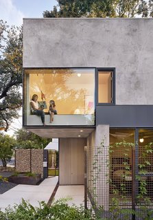 Windows and skylights have been strategically placed throughout to capture striking views of the surrounding trees. Here, a bedroom cantilevers above the entrance patio.