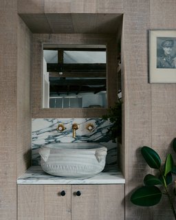 In the bathroom, a small antique marble basin is nestled within a limed oak alcove.