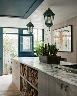 For the kitchen, Arabescato slabs with little butterfly joints are combined with a large dresser with twisted brass pulls and shelves for firewood storage. 