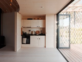 On one side of this large entrance is a kitchen that’s concealed by wooden doors and panels when not in use.