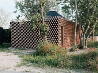 Surrounding the deck at the entrance of the cabin is a lattice-wood frame that serves as a shelter for the outdoor area. 