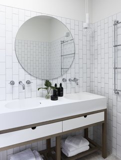 Subway tiles have been laid in a vertical pattern in the bathroom to echo the height of the palm trees just outside this area. 