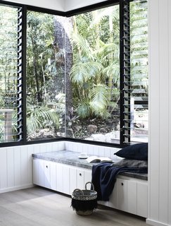 The exterior has wrapped in a black cladding with gray render. Large expanses of glazing create a strong visual connection to the forest outdoors.