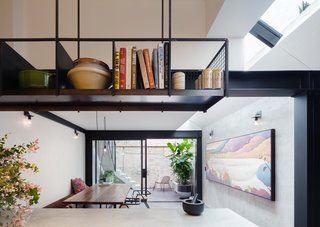 Behind the library wall, and beyond the switchback staircase, is a kitchen and dining area that opens out to a streamlined courtyard with a herringbone brickwork floor. 