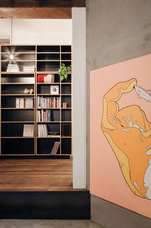 In the library, black plywood joinery offers a pause from the entryway before the floorplan pivots to reveal a sunken concrete living area in the original front room.
